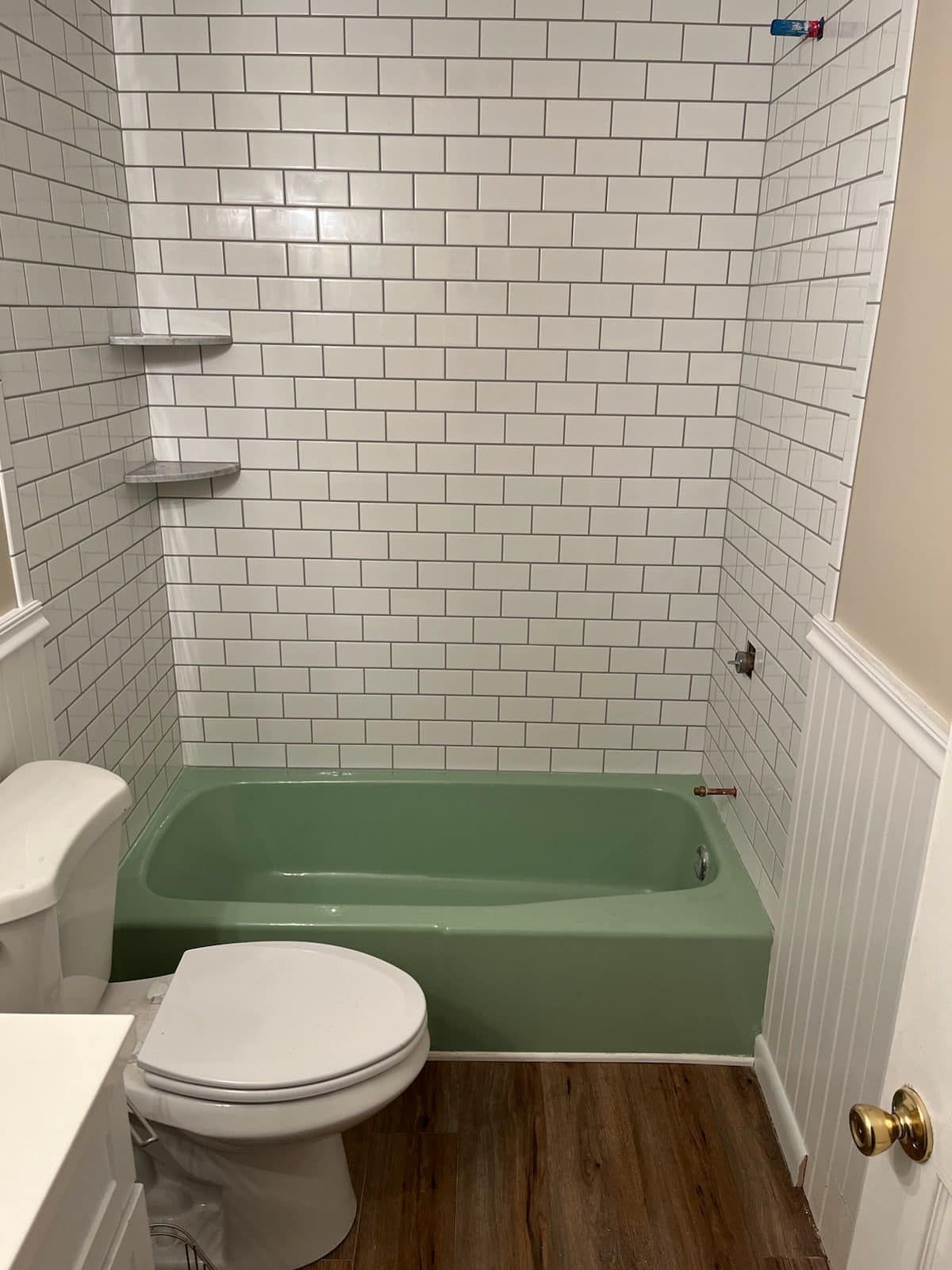 A bathroom with a toilet , bathtub and white brick walls.