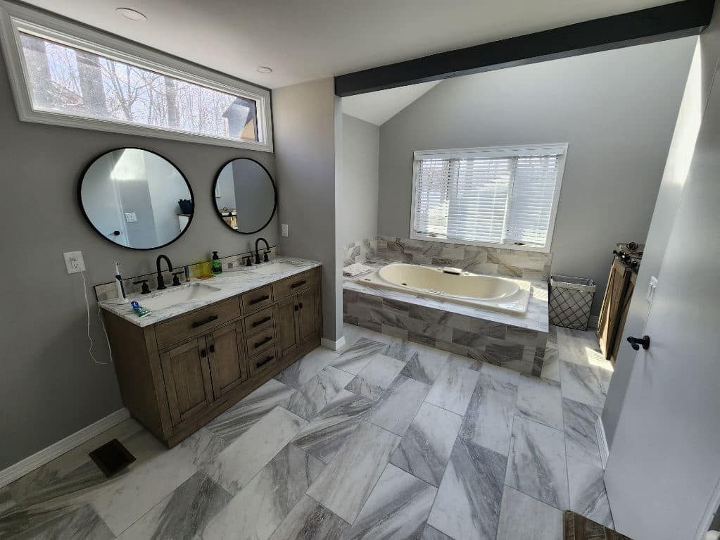 A bathroom with two sinks , a tub and two mirrors.