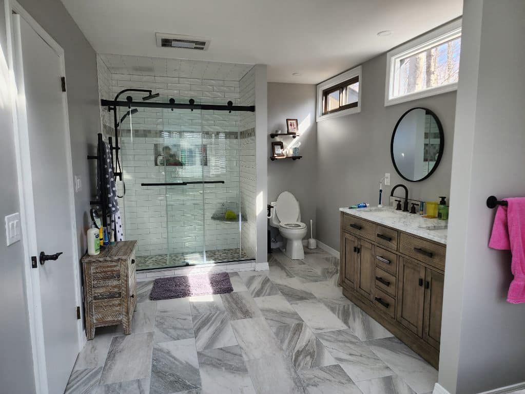 A bathroom with a walk in shower , sink , toilet and mirror.