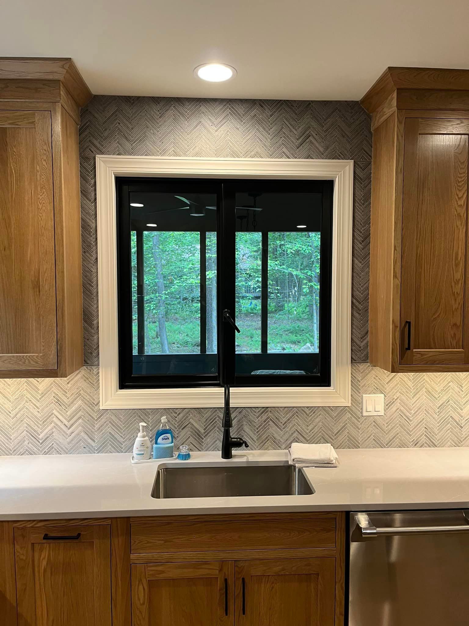 A kitchen with a sink , dishwasher , and window.