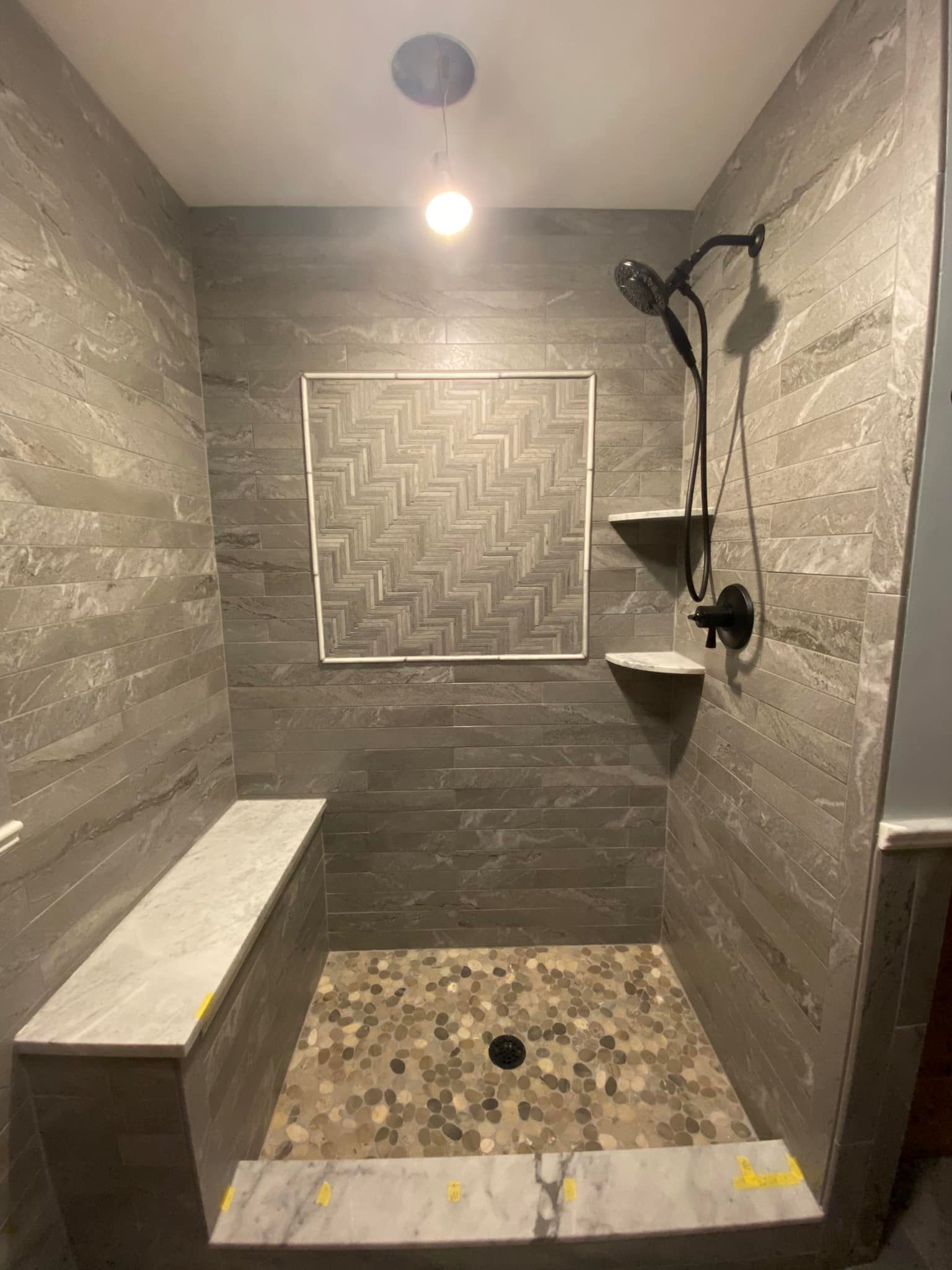 A shower with a bench and a shower head in a bathroom.