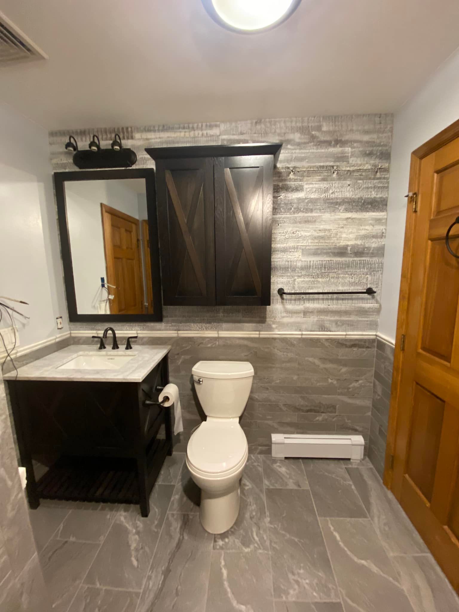 A bathroom with a toilet , sink and mirror.