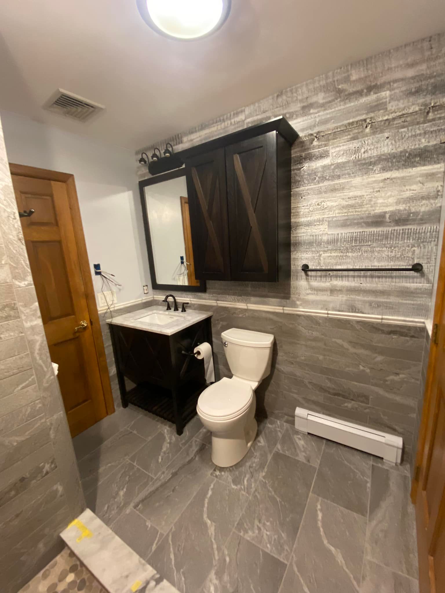 A bathroom with a toilet , sink and mirror.
