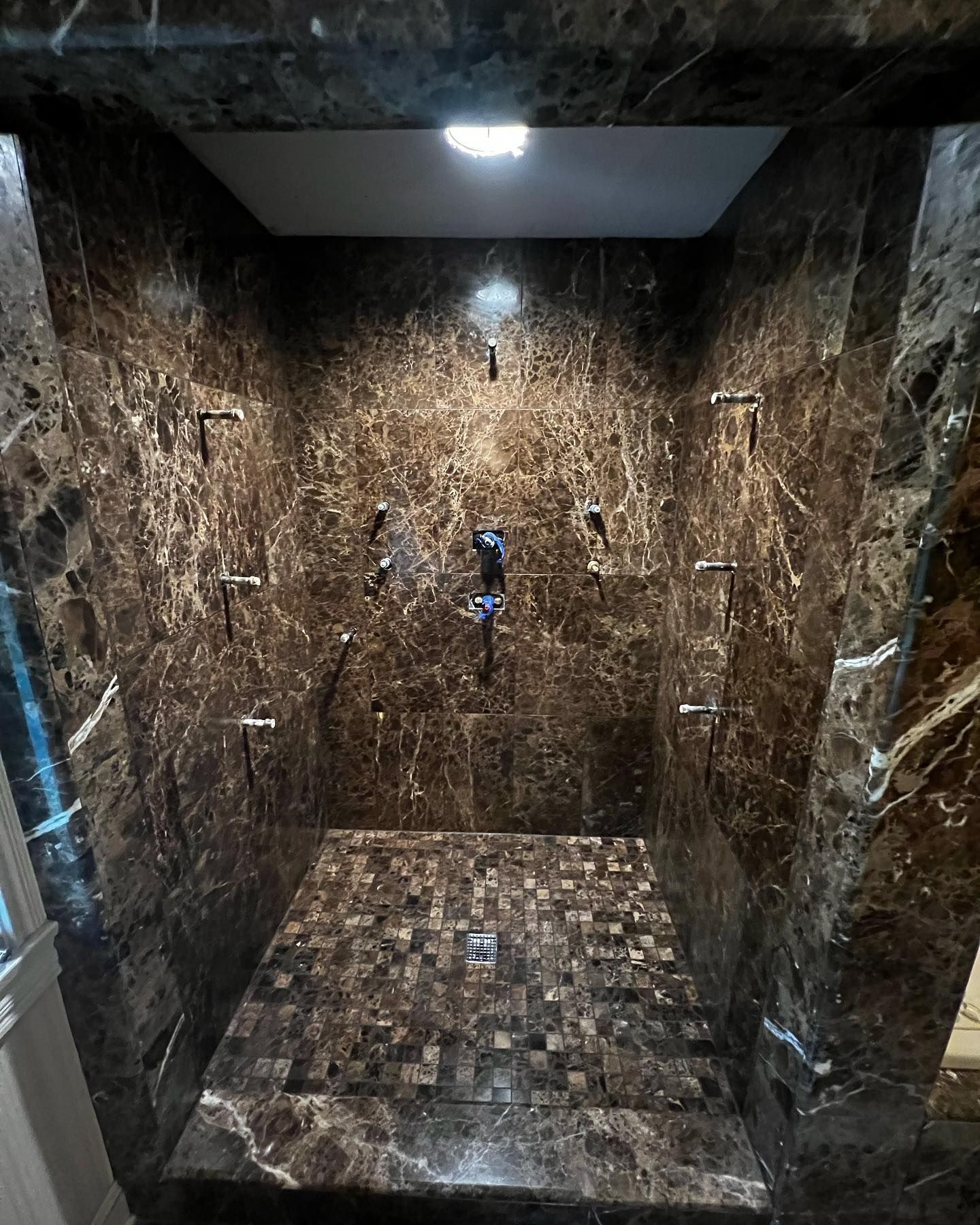A bathroom with marble walls and a walk in shower.