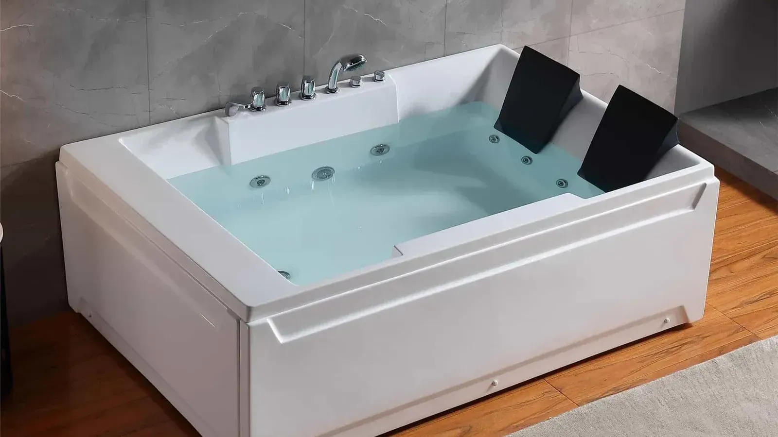 A white bathtub is sitting on a wooden floor in a bathroom.