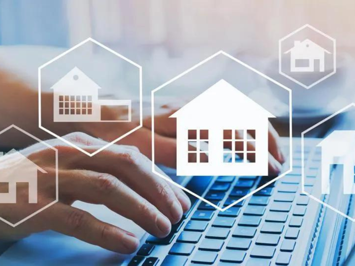 A person is typing on a laptop with a house icon on the screen.