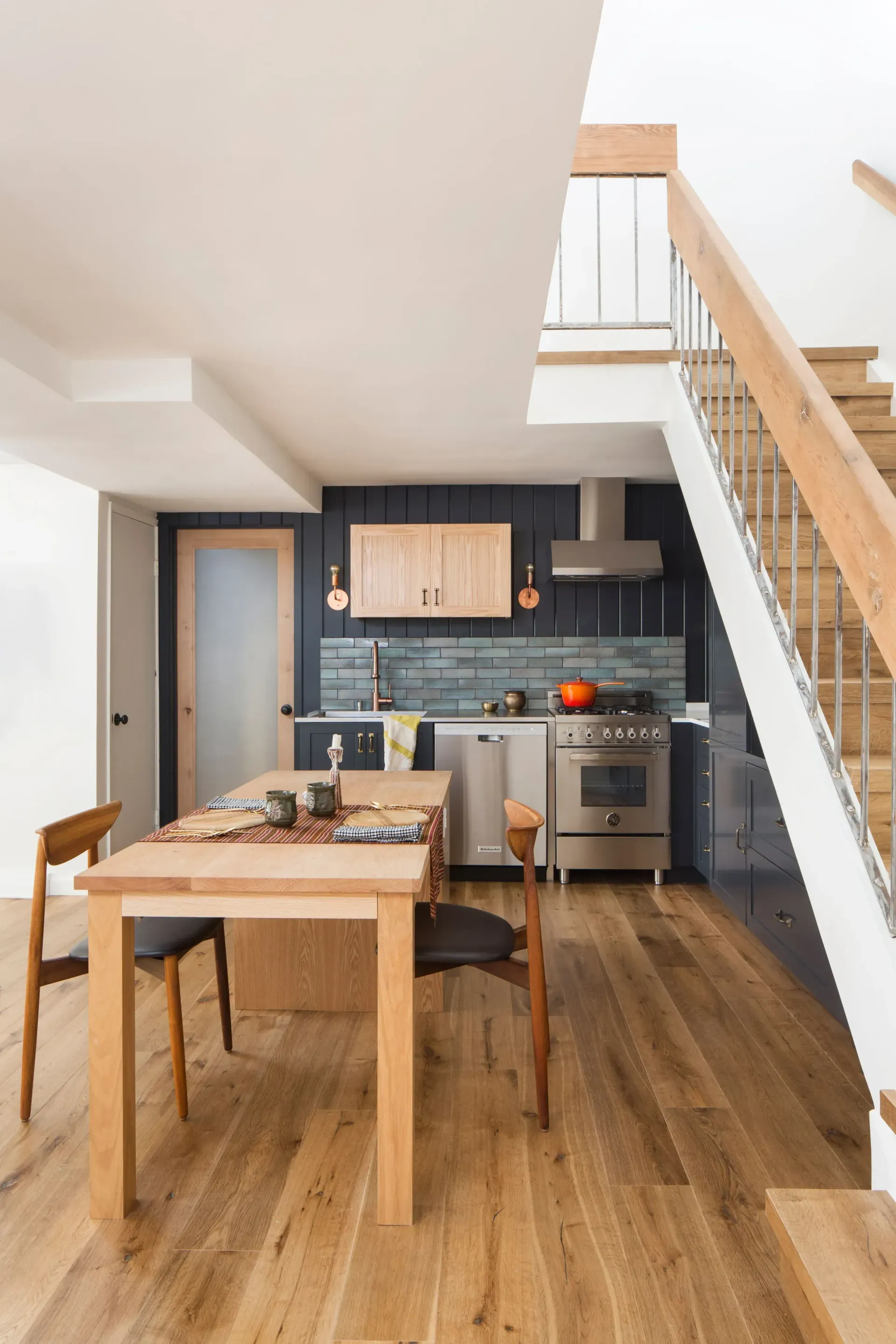 A kitchen with a table and chairs and stairs leading up to the second floor.