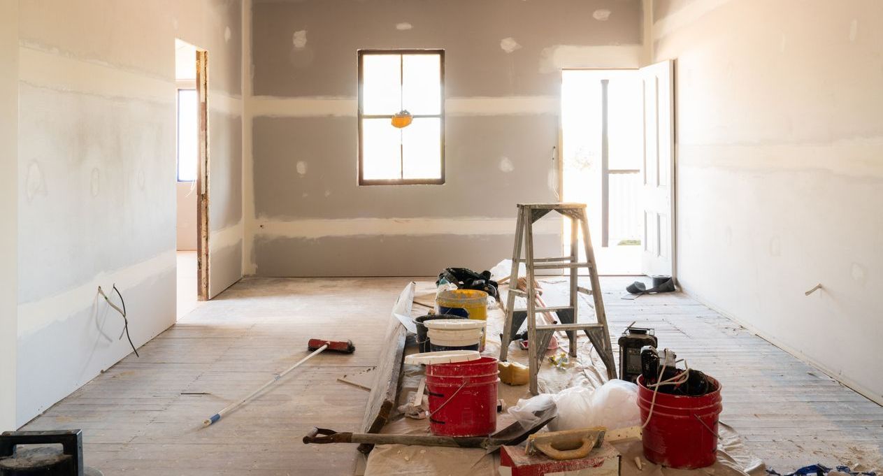 A room under construction with buckets of paint and a ladder.