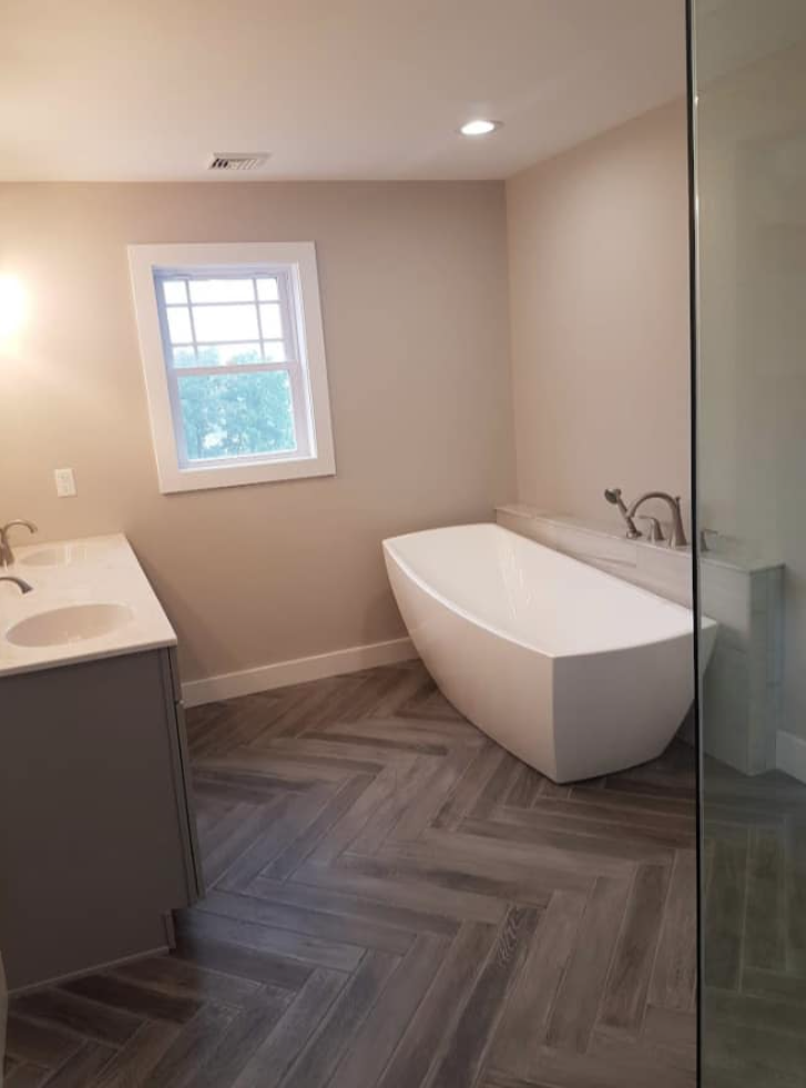 A bathroom with a bathtub , sink , and window.