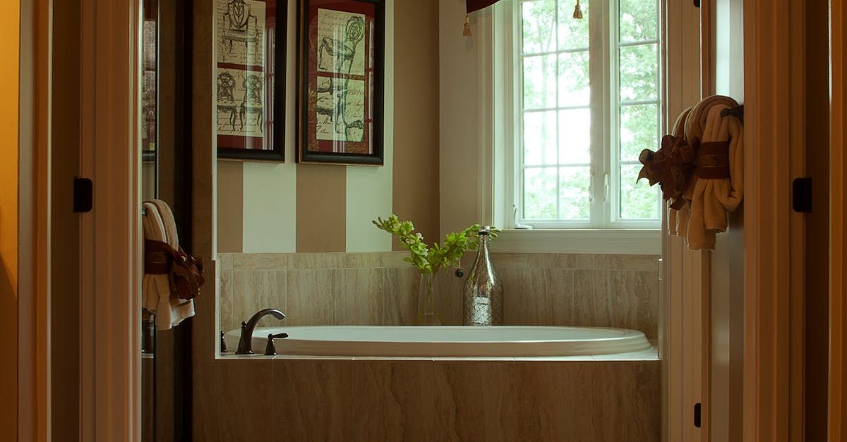 A bathroom with a tub , sink , mirror and window.