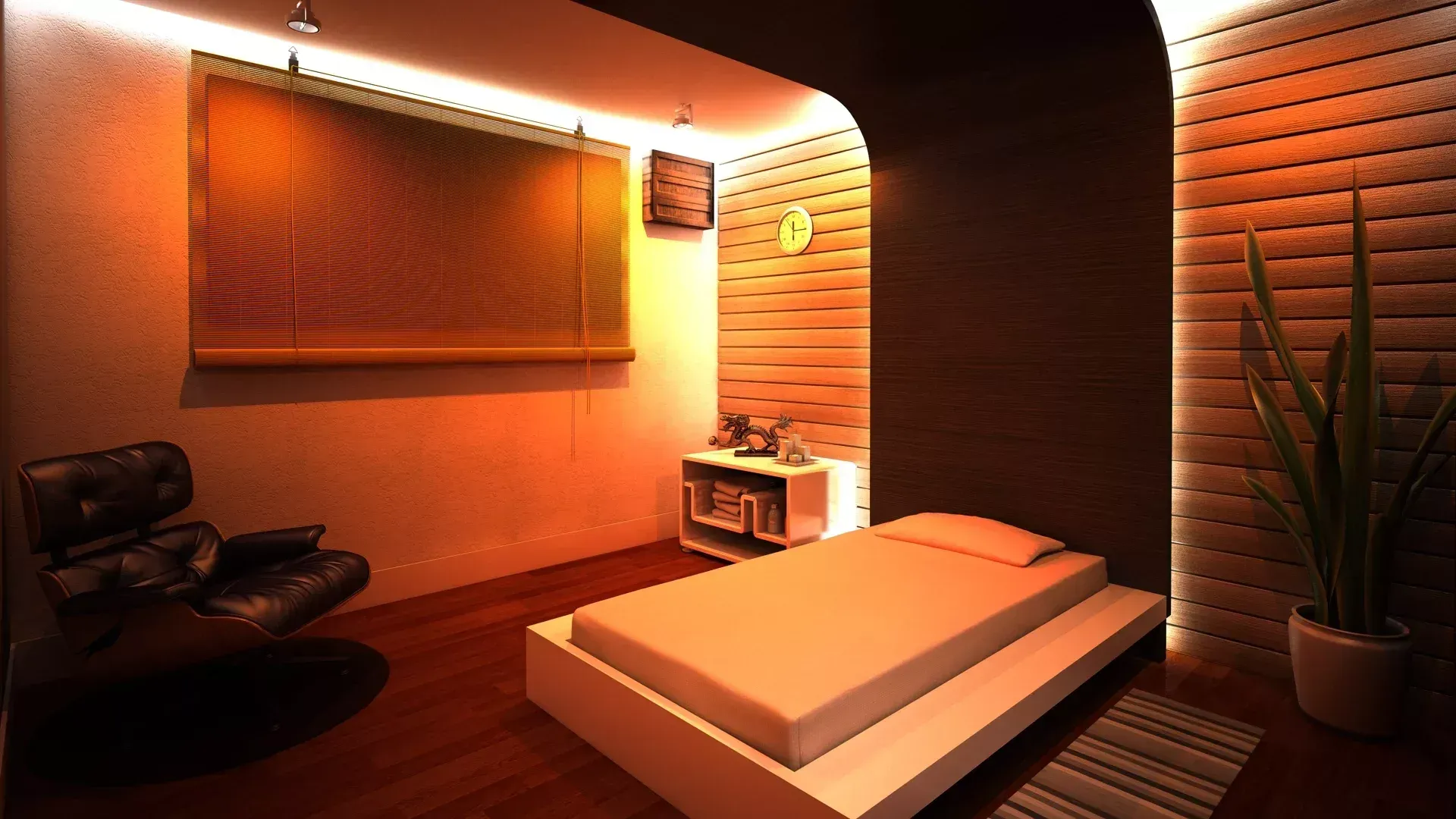 Um quarto aconchegante com uma cama baixa tipo plataforma, uma poltrona de couro preta, iluminação ambiente e uma planta.