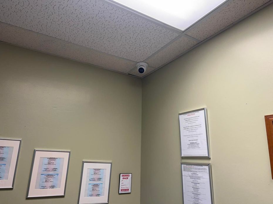 A room with pictures on the wall and a camera on the ceiling.