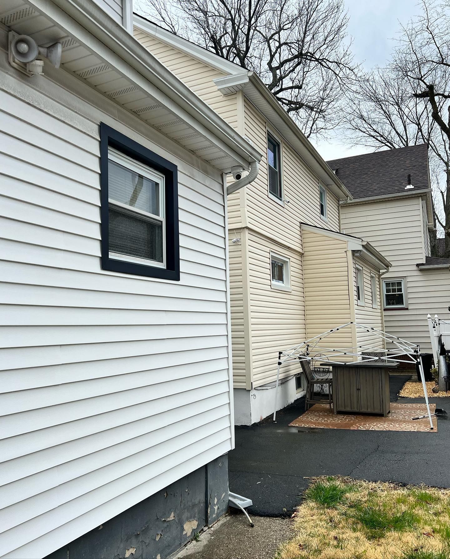 A white house with a black window and a black gutter.
