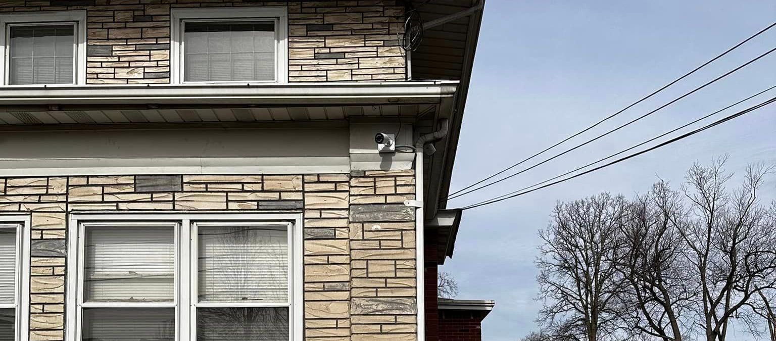 A brick house with a lot of windows is next to a power line.