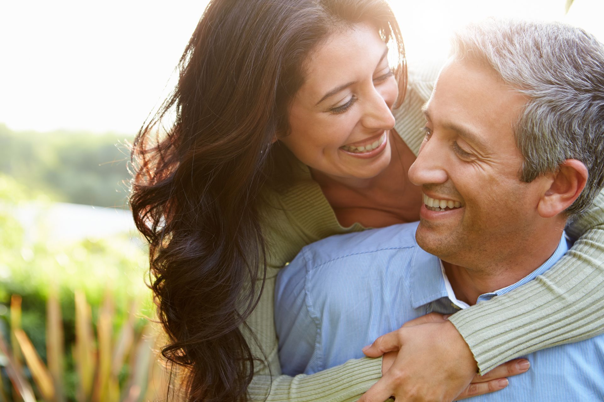 Two people smiling and hugging outdoors in warm sunlight