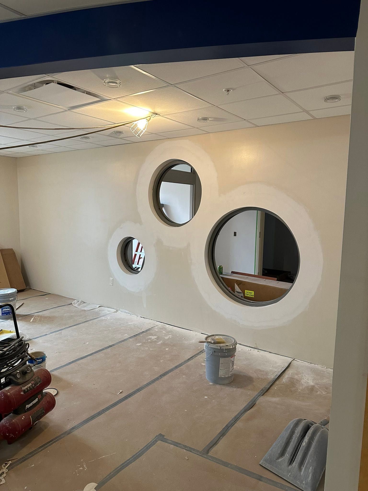 Partially renovated room with three round wall windows and construction materials on the floor
