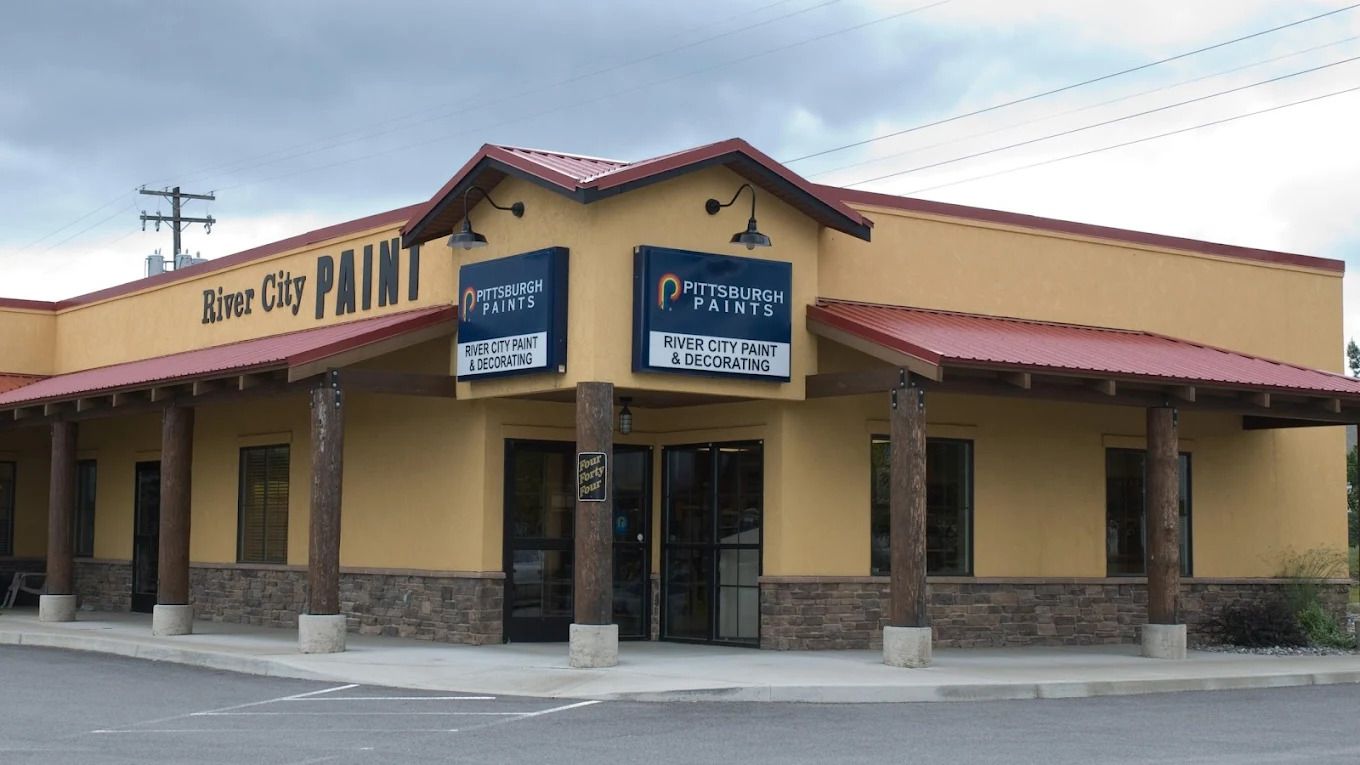 Corner storefront with tan stucco walls, red roof, and blue signs on a street corner.