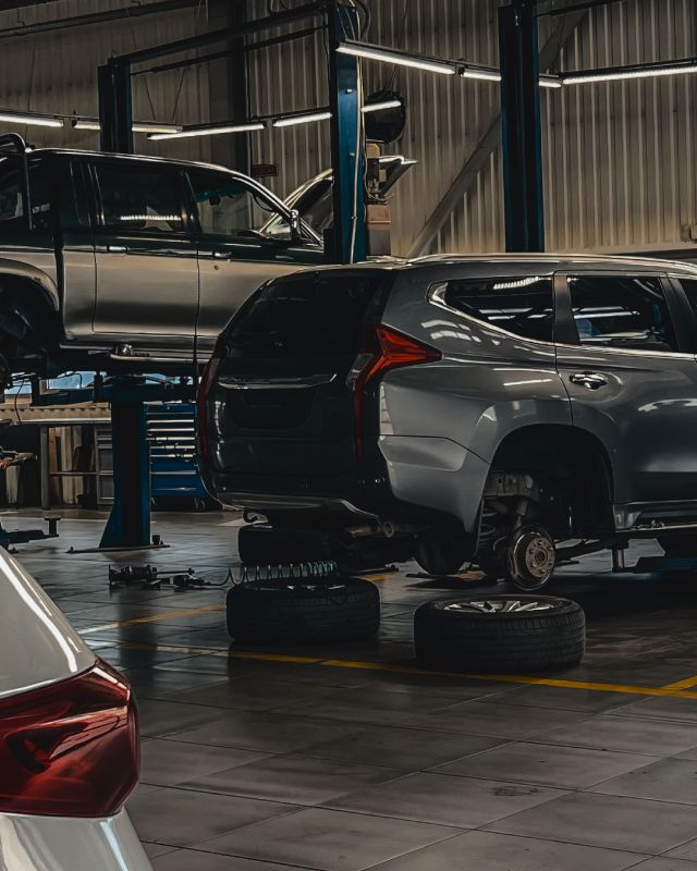 SUVs in a repair garage, one on a lift and one with a wheel removed | Rick's Auto Shop