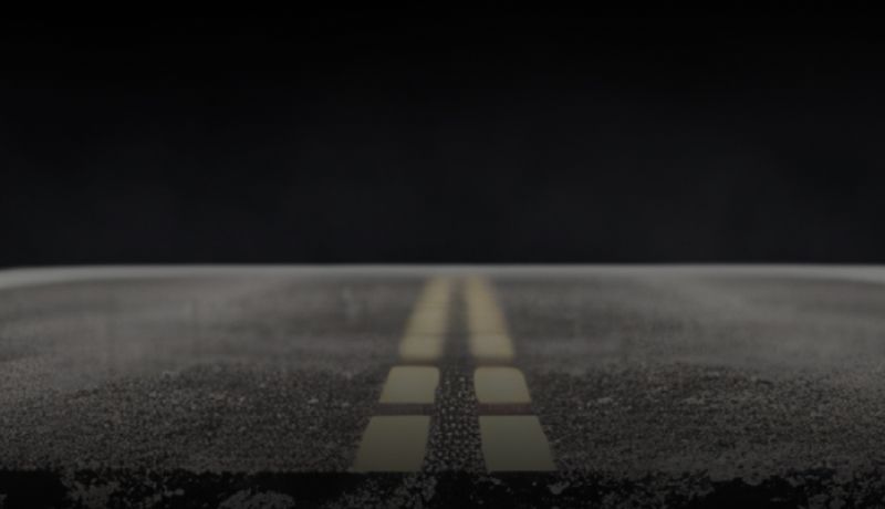 Empty road at night with double yellow center lines fading into darkness | Rick's Auto Shop