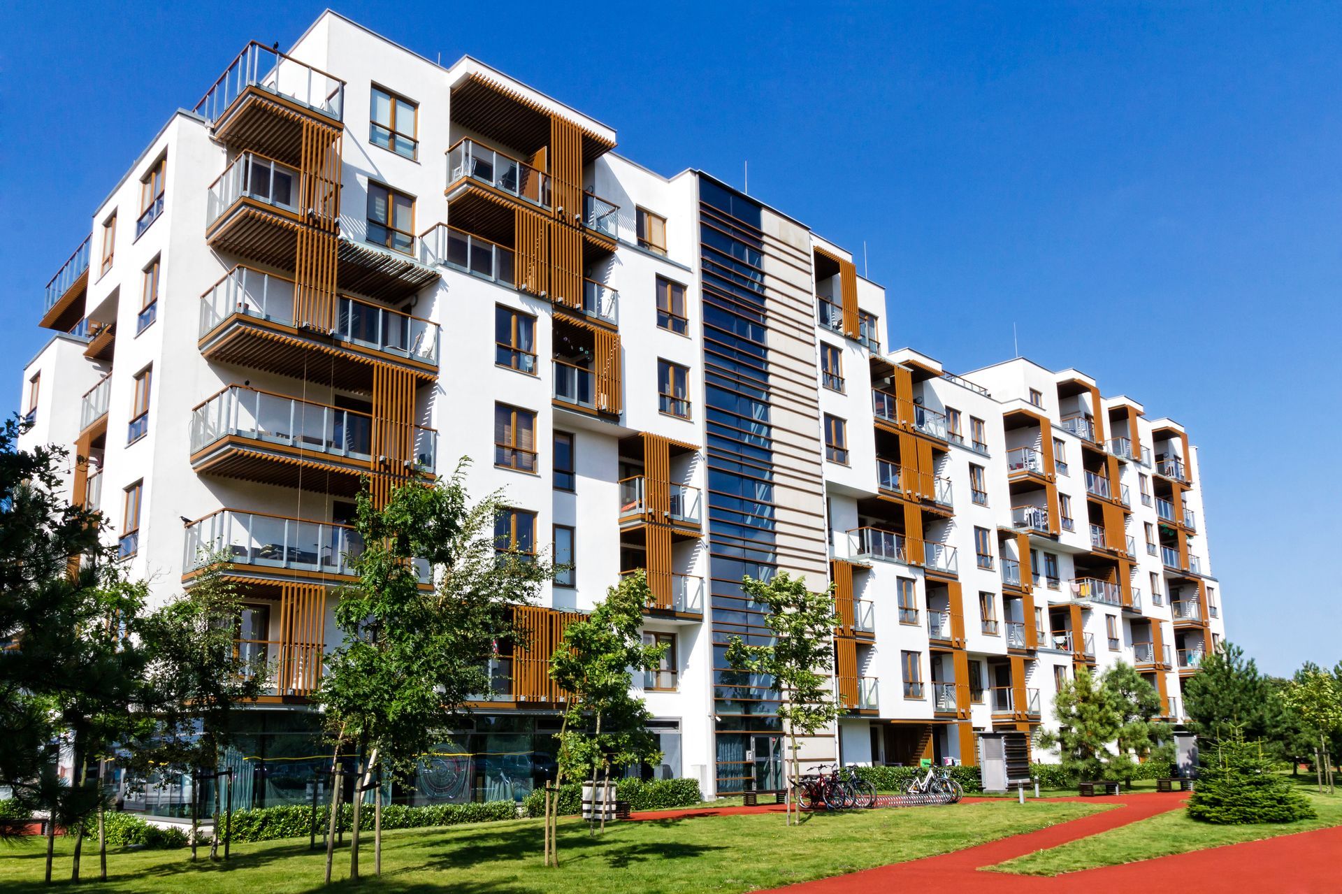 A large apartment building with lots of balconies and trees in front of it.