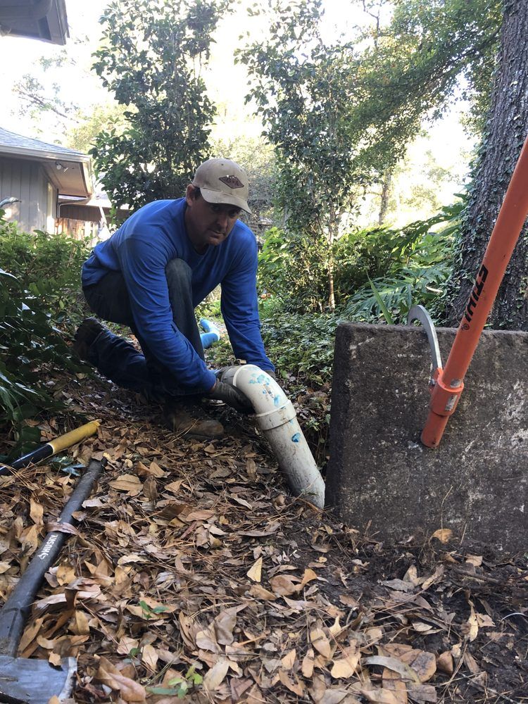 a man in a blue shirt is working on a pipe with a shovel that says stihl on it