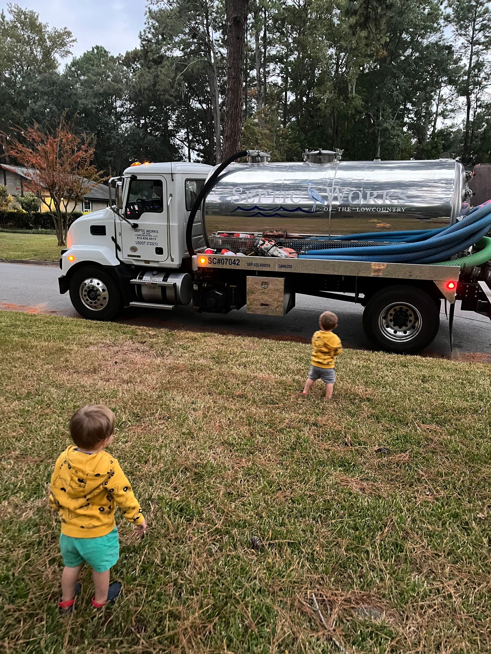 two children are standing in front of a septic truck that says septic in the low country