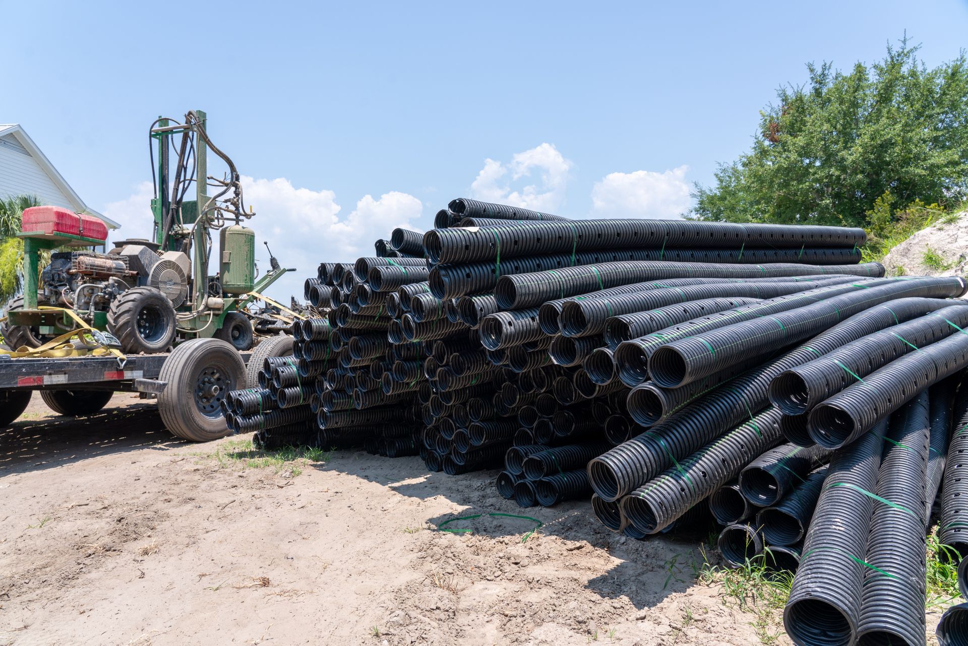 a stack of black pipes sits next to a tractor