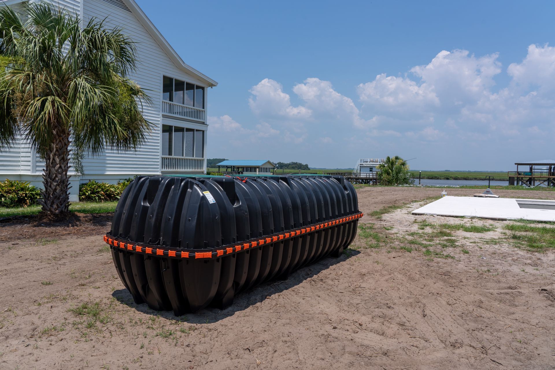 a large black tank sits in the dirt in front of a house