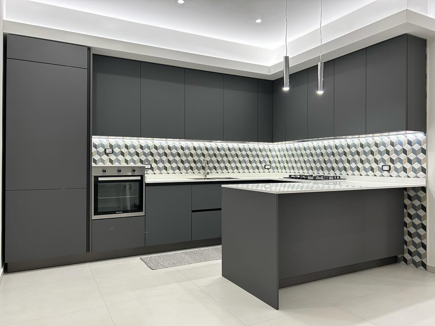Una cucina con mobili grigi e ripiano bianco.