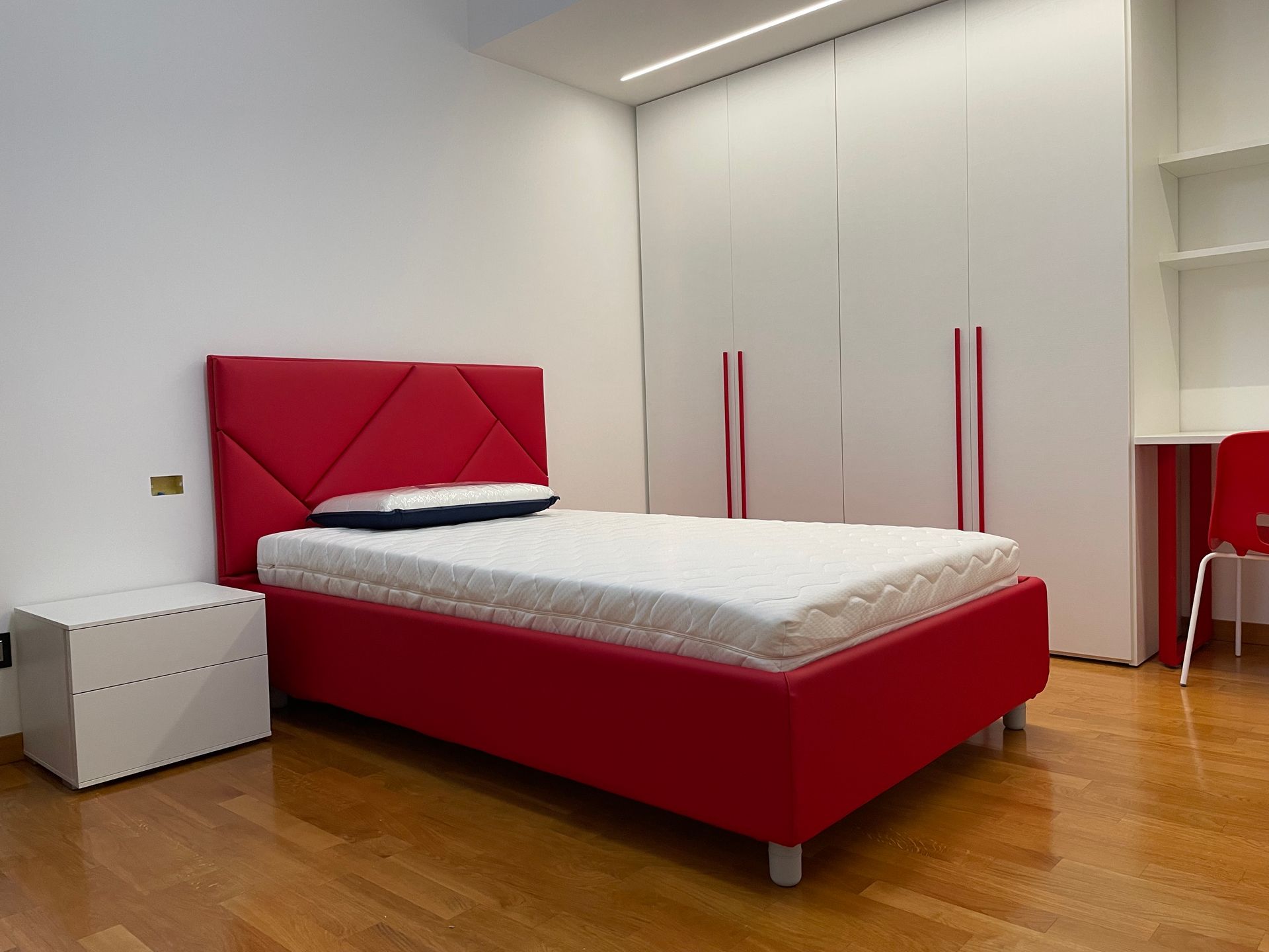 Una camera da letto con letto rosso e pareti bianche