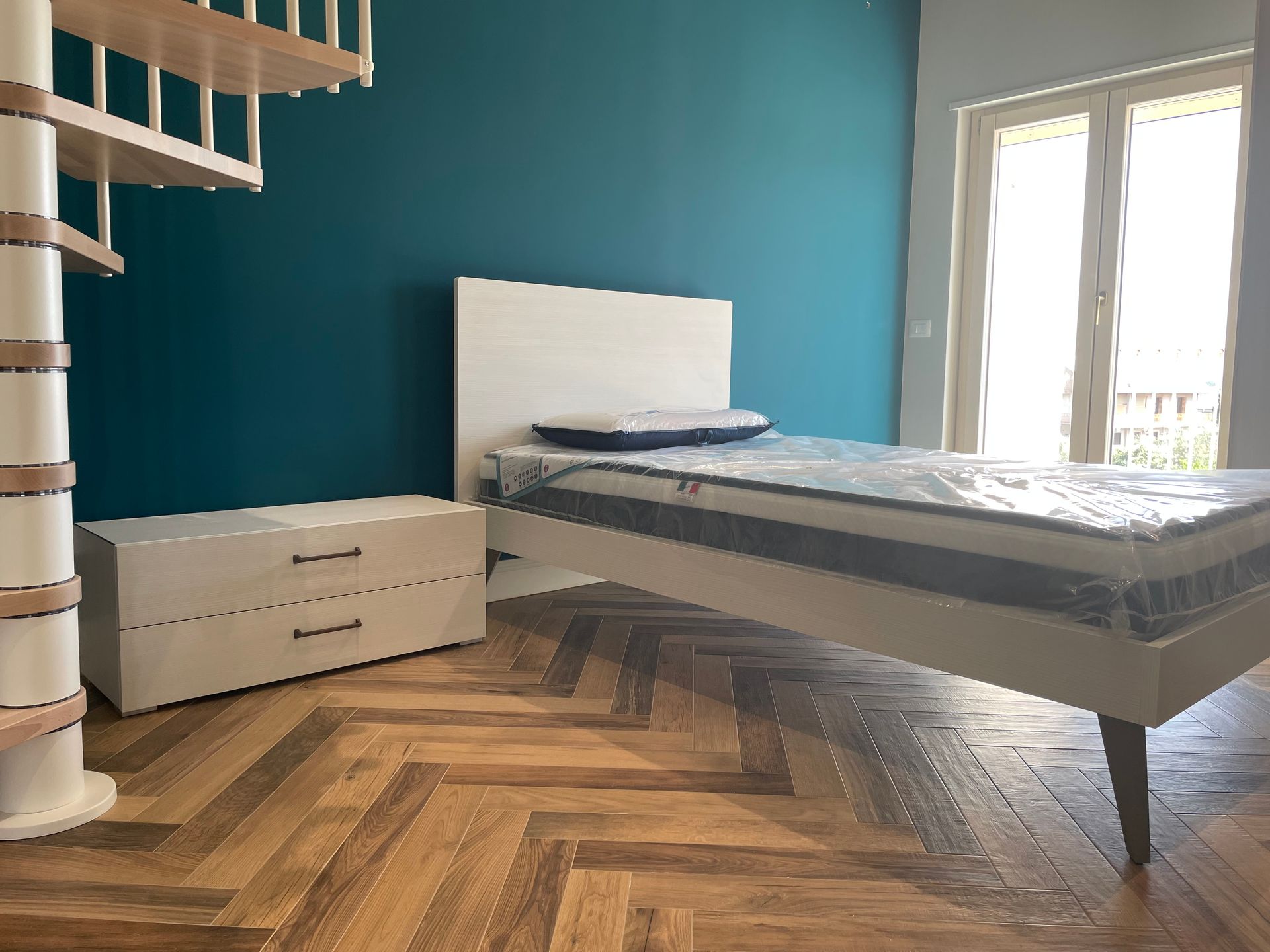 Una camera da letto con letto, cassettiera e scale.
