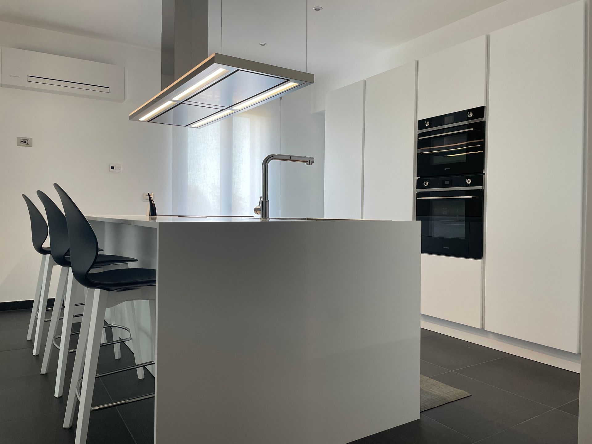 Una cucina con mobili bianchi e sedie nere