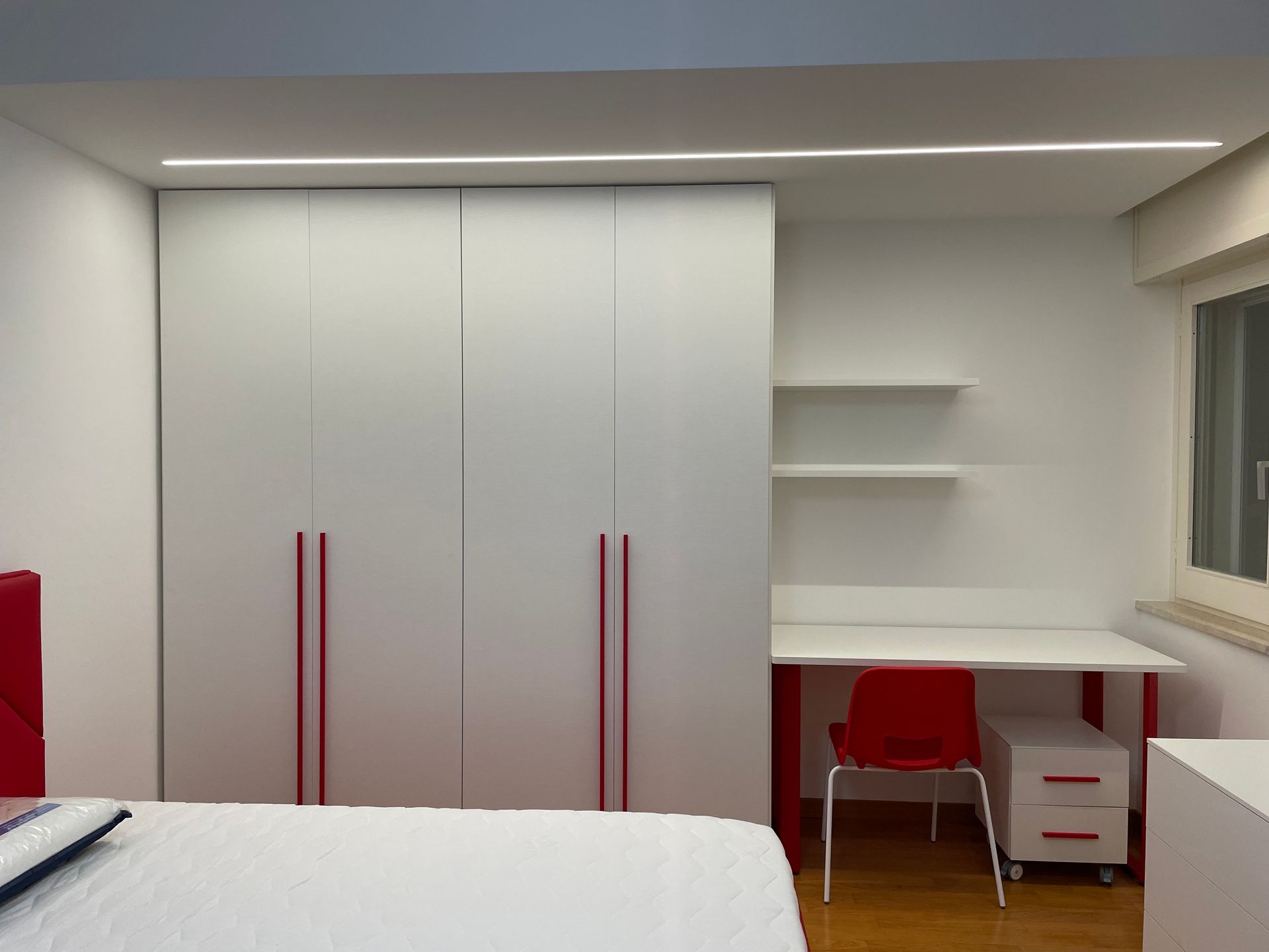 Una camera da letto con un letto e una scrivania con maniglie rosse