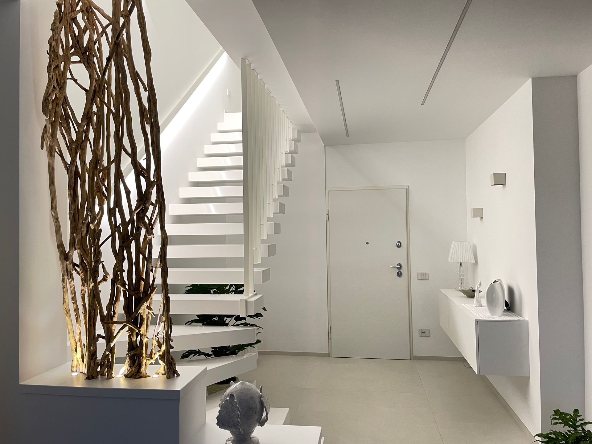 Un corridoio bianco con una scala e una porta