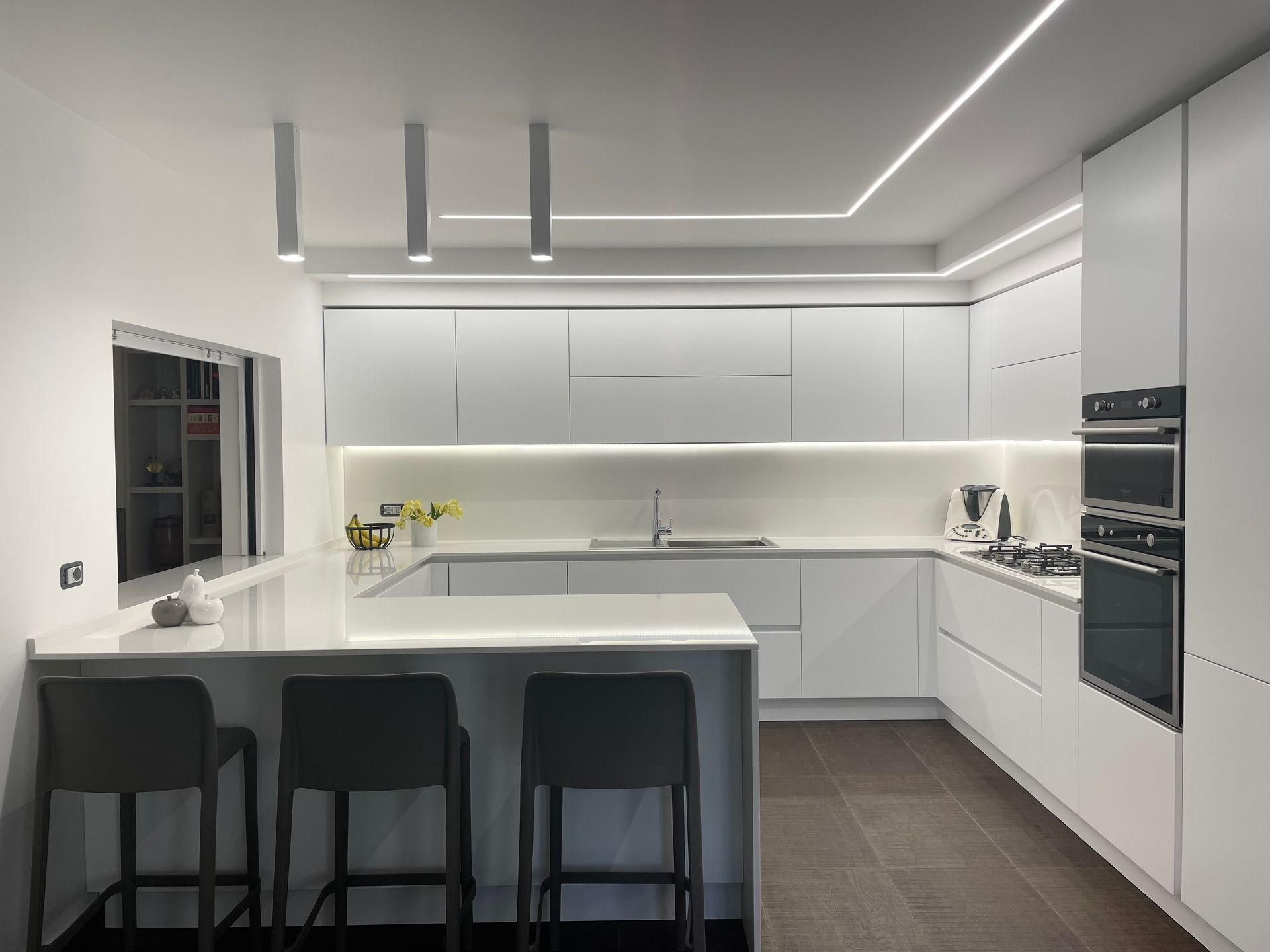 Una cucina moderna con mobili e sgabelli bianchi
