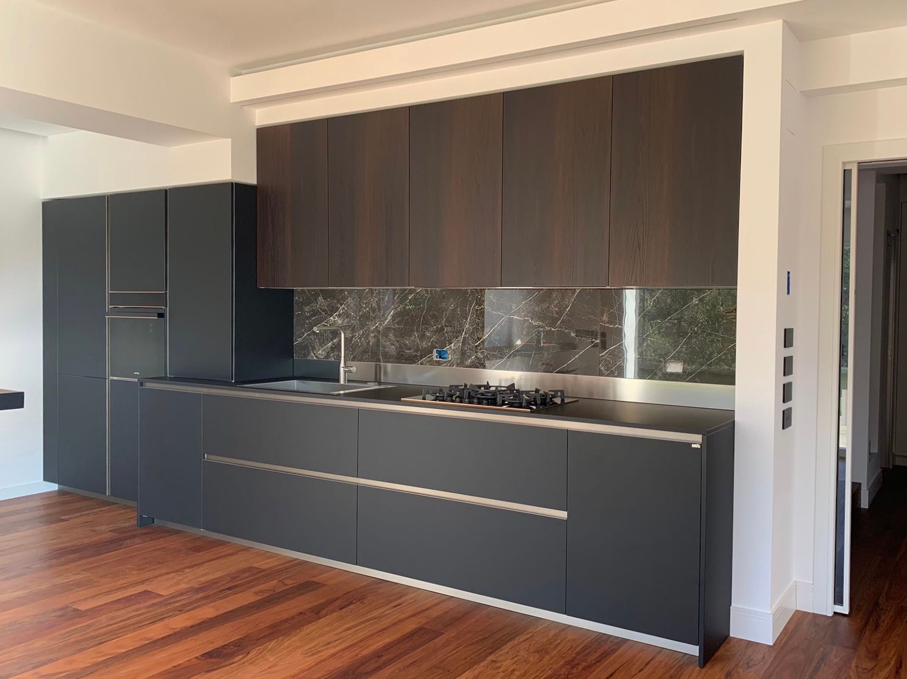 Una cucina con elettrodomestici in acciaio inossidabile e pavimenti in legno.