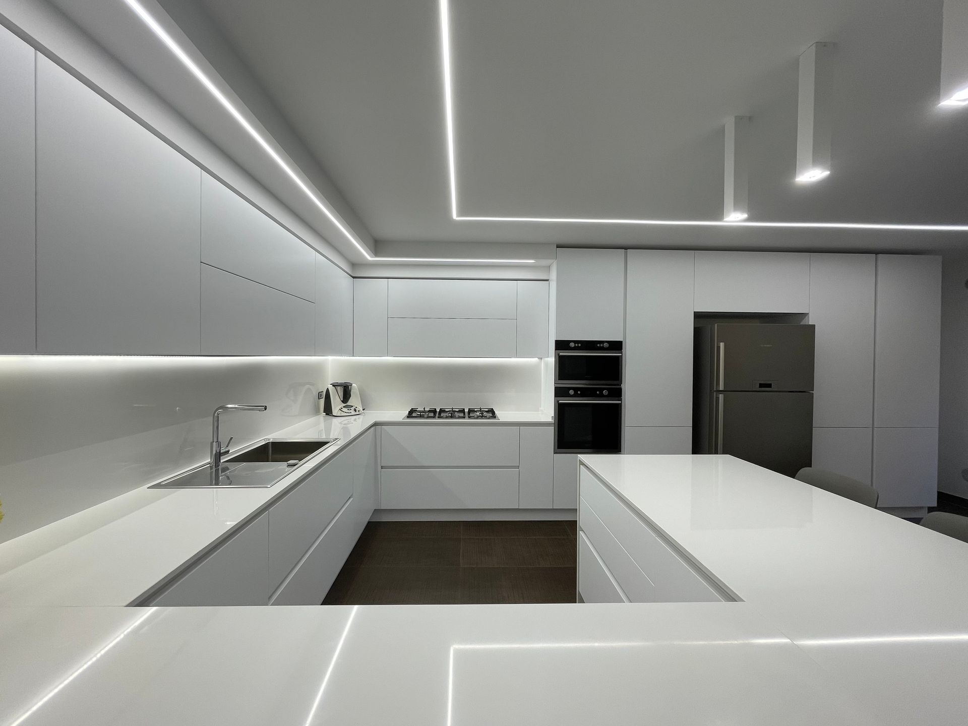Una cucina con mobili bianchi e ripiani bianchi