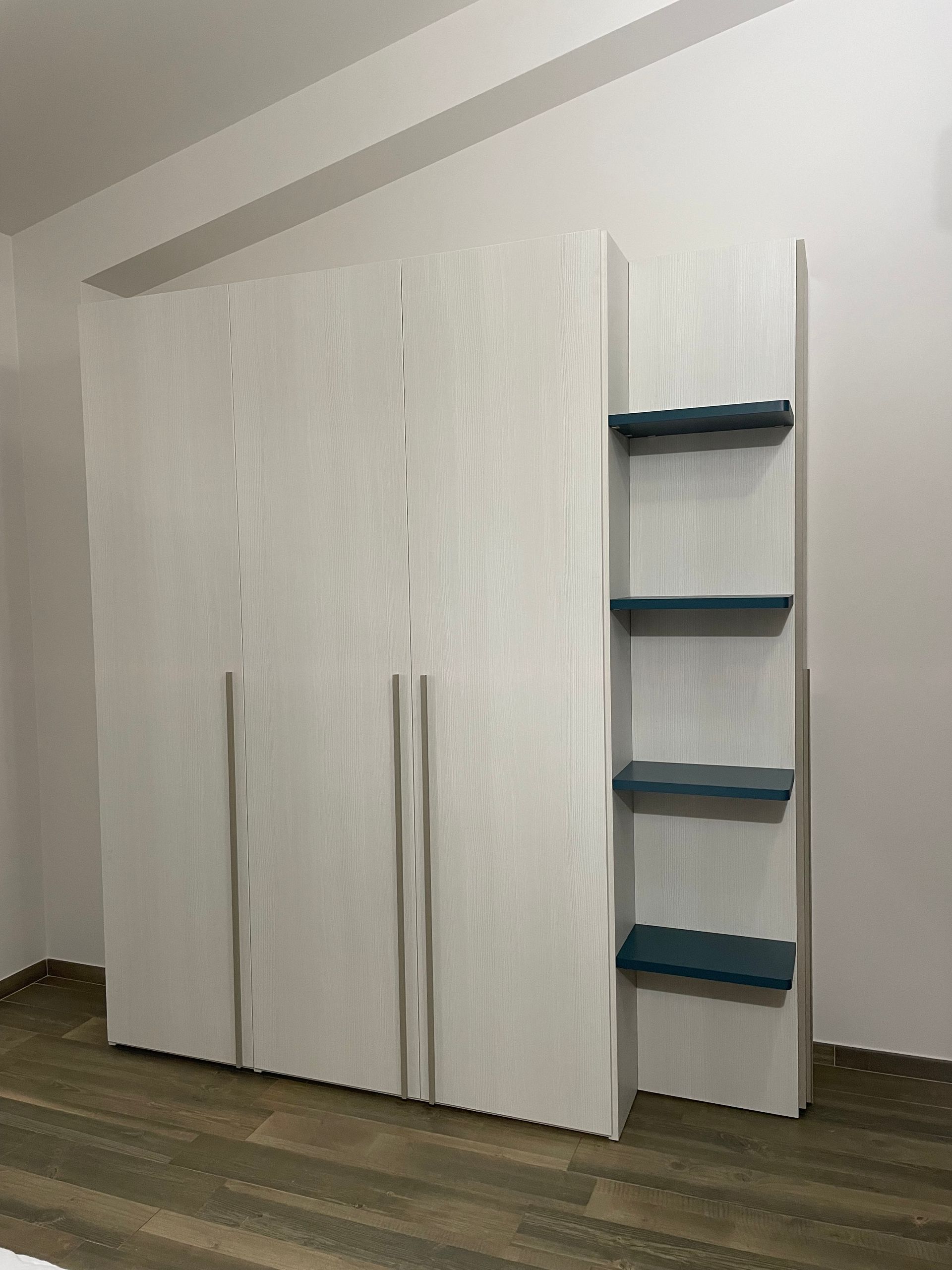 Una camera da letto con armadio bianco e scaffali blu
