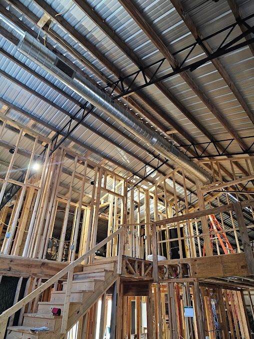 Interior of a house under construction with exposed framing, stairs, and metal roof beams