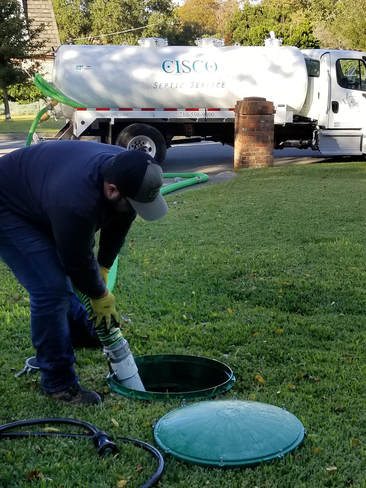 Expert plumber opening a riser for a septic tank inspection.