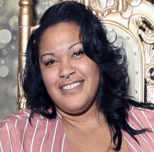 A woman with a nose ring is smiling while sitting in a chair
