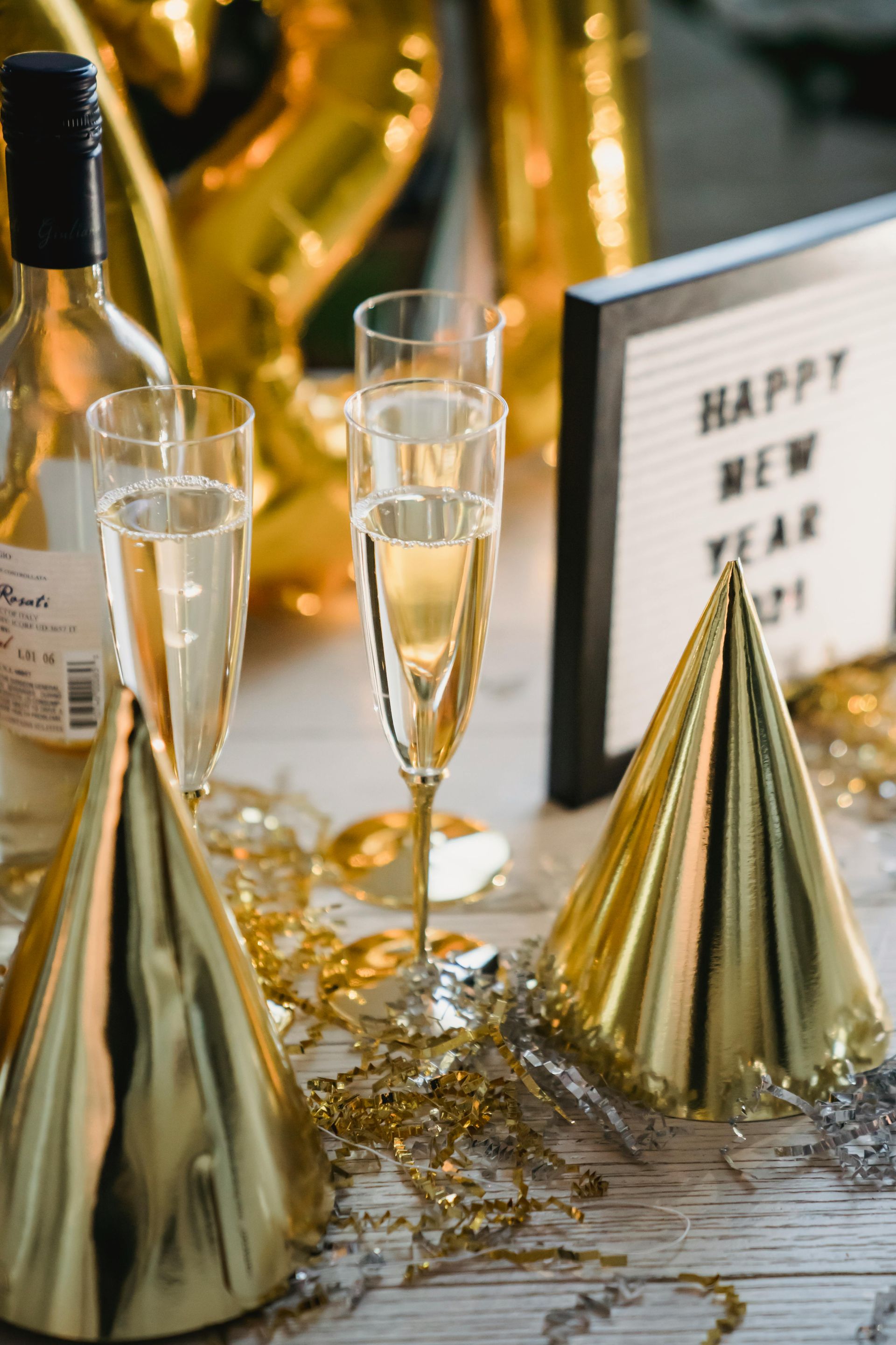 A table topped with glasses of champagne , party hats , and balloons.