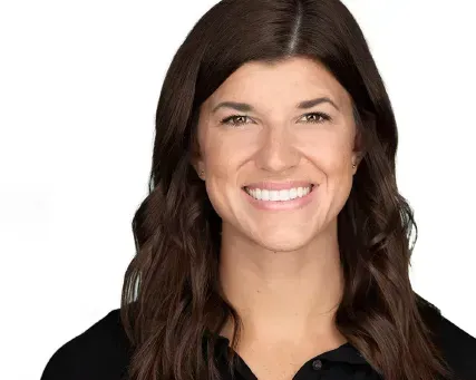 Smiling woman with long dark hair on a white background, wearing a black top