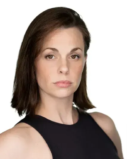 Portrait of a person with dark shoulder-length hair in a black sleeveless top, looking at the camera.