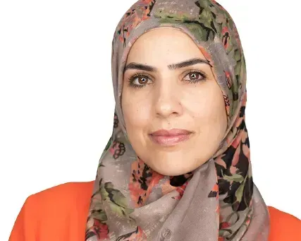 Portrait of a woman in a patterned headscarf and orange top against a white background