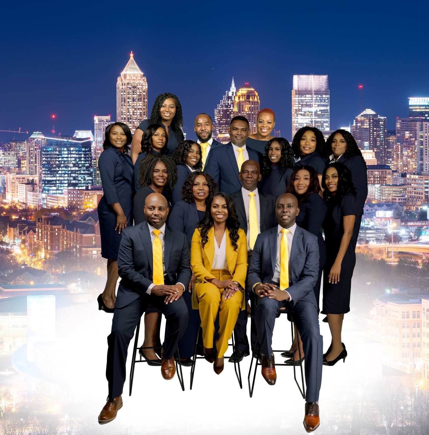 Group of people posing in formalwear with a city skyline at night in the background.
