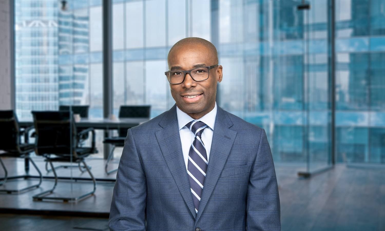 Businessman in a blue suit smiling in a modern office with glass walls