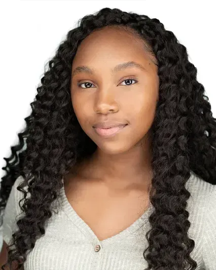 Portrait of a person with long curly hair wearing a light gray sweater, against a white background