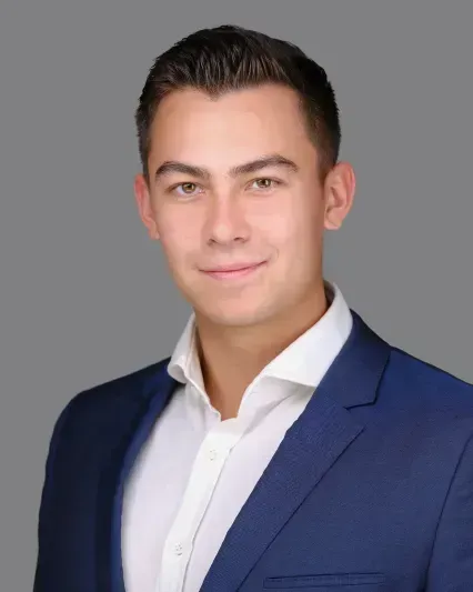 Headshot of a person in a blue suit jacket and white shirt against a gray background