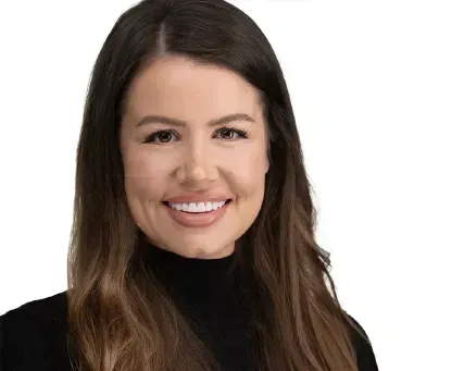 Smiling woman with long brown hair wearing a black turtleneck against a white background